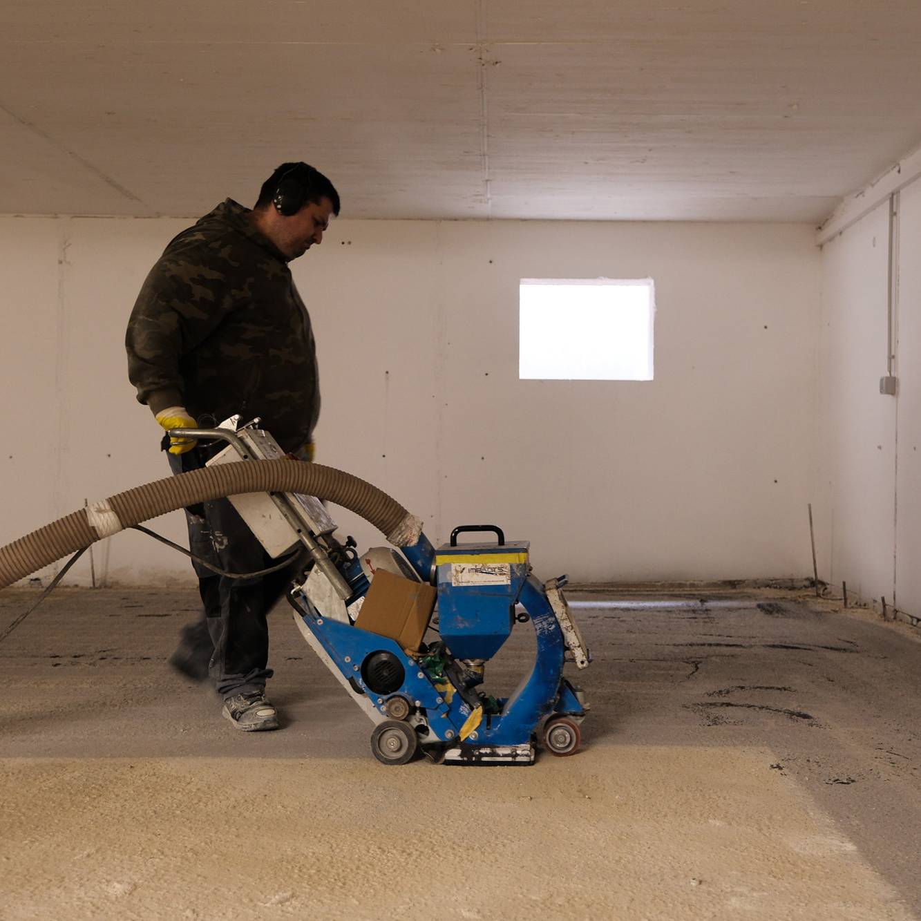 Mitarbeiter kugelstrahlt einen Tiefgaragenboden.