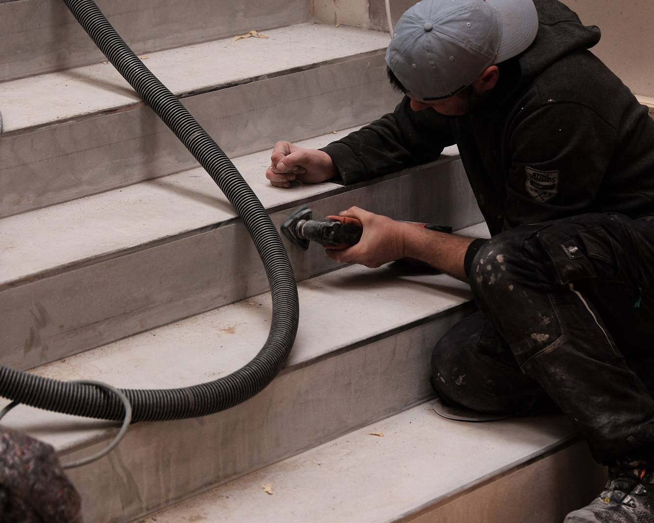 Mitarbeiter schleift die neue Treppe aus Sichtestrich.