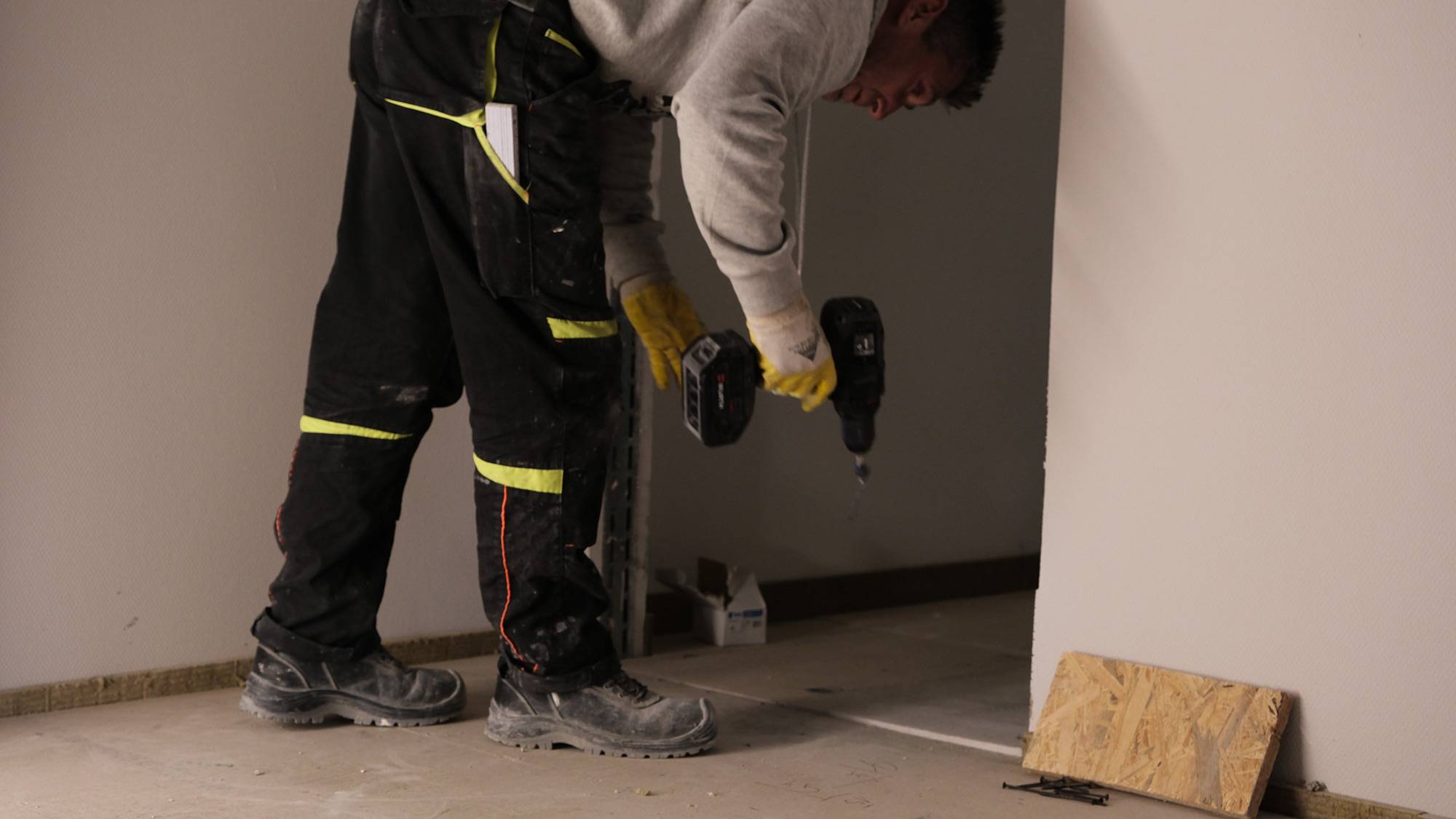 Mitarbeiter verlegt auf einer Baustelle Trockenestrich.